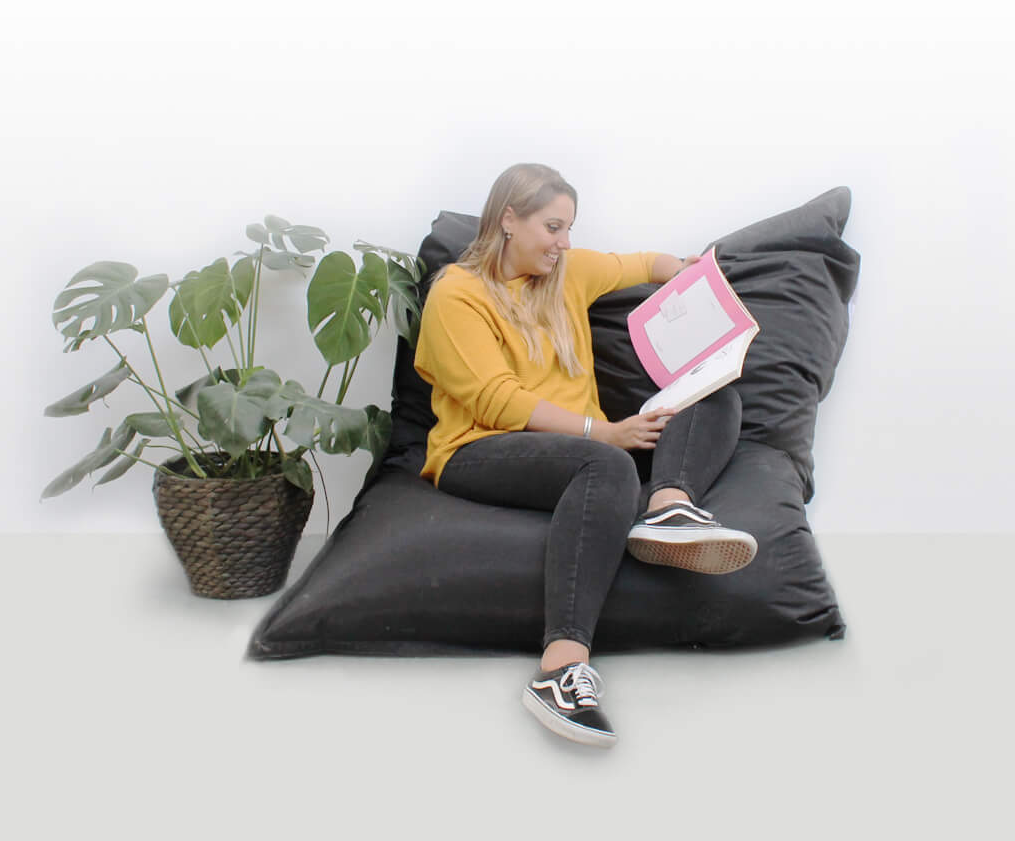 Andree is reading while sitting relaxed on a beanbag.